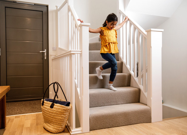 A young girl runs down the stairs in a modern electric home.