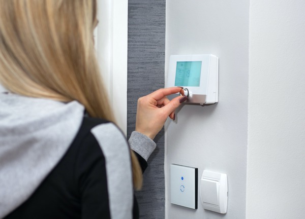 Woman using heating thermostat
