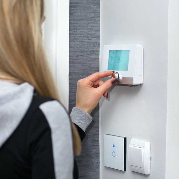 Woman using heating thermostat