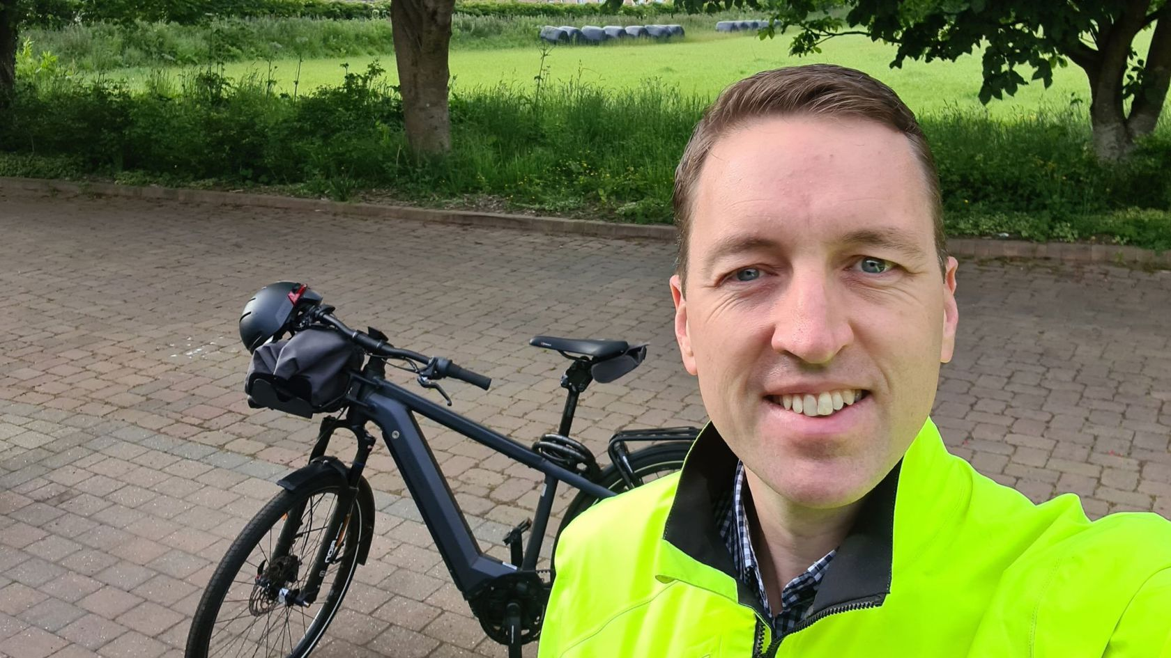 Stuart Murphy, Jrsey Electricity Head of Customer Experience and Communications. wearing a reflective jacket standing next to his electric bike