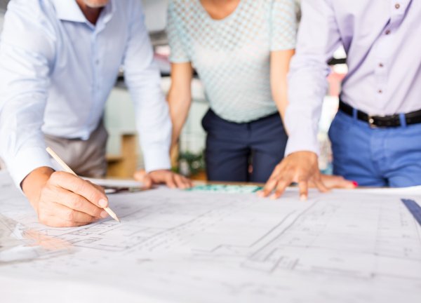Three engineers look at a set of buidling drawings.